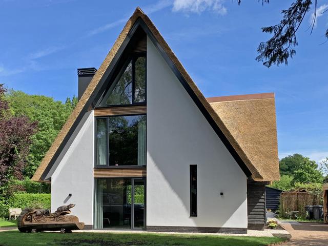 Villa met een rieten kap, aluminium kozijnen met daartussen
Platowood
