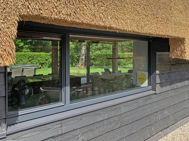 het kozijn in de keuken geeft een doorkijk naar het zij-erf.
Hiervoor is het riet weggeschoren